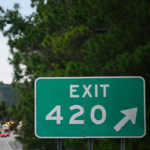 a green exit sign sitting on the side of a road.