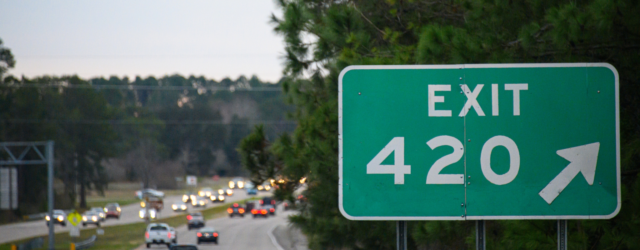 a green exit sign sitting on the side of a road.