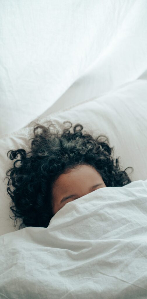 a woman laying in bed under a blanket.