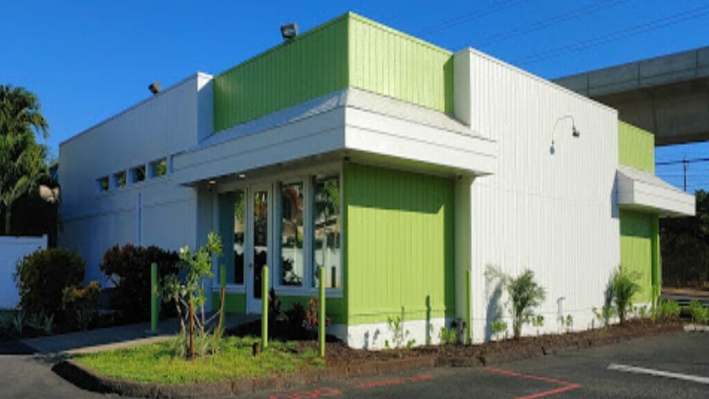 a green and white building sitting on the side of a road.