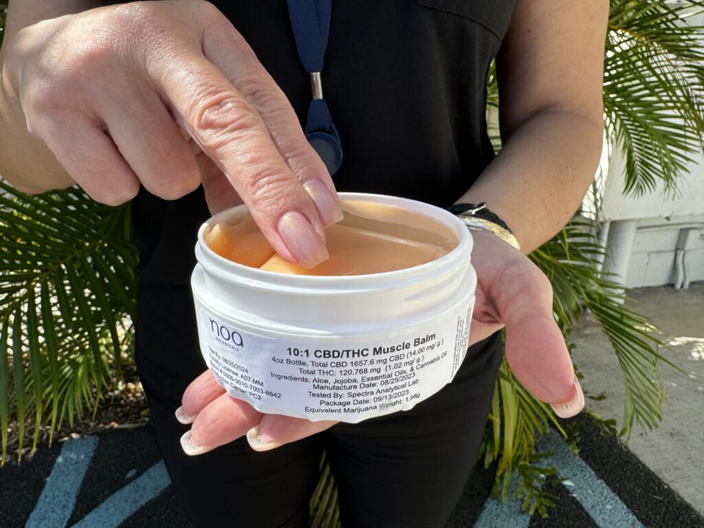 A woman holding a jar of a cream.