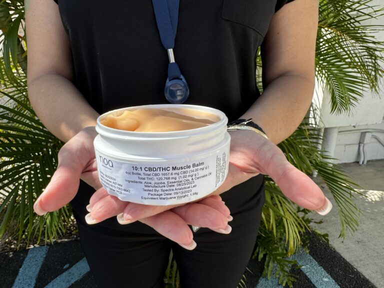 A woman holding a jar of CBD muscle balm.