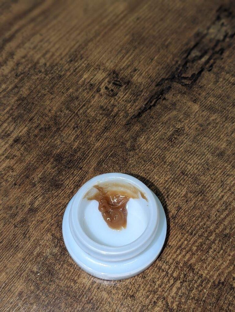 A small container with a brown lid sitting on top of a wooden table.